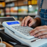 Commerçant calculant ses factures et charges au comptoir de sa boutique